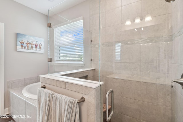 bathroom with a garden tub and a tile shower