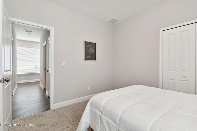 bedroom featuring a textured ceiling, visible vents, baseboards, a closet, and dark carpet