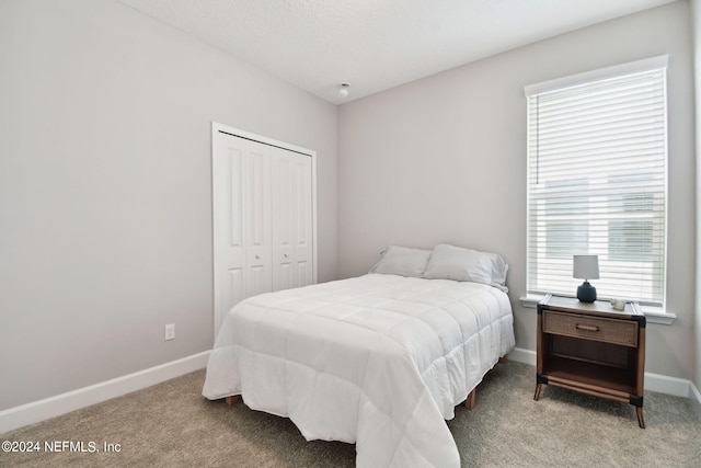 bedroom with carpet floors, baseboards, and a closet