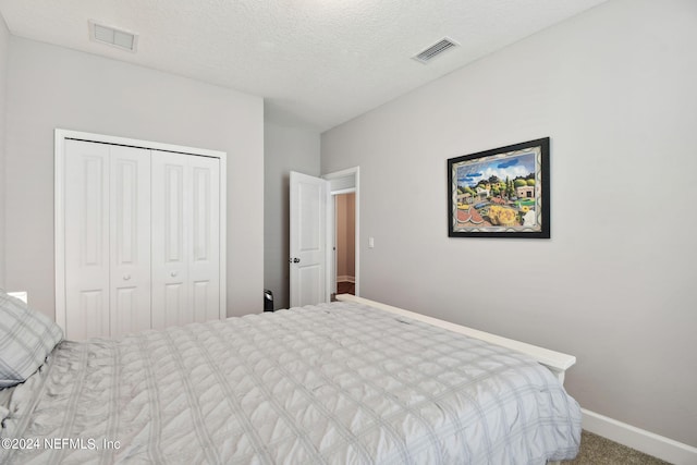 carpeted bedroom featuring baseboards, a textured ceiling, visible vents, and a closet