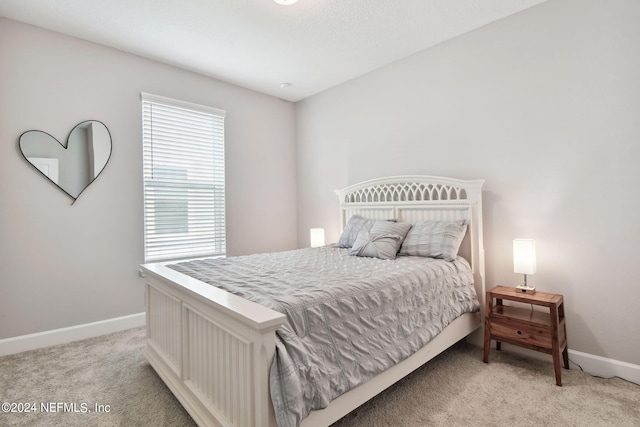 bedroom with baseboards and light colored carpet