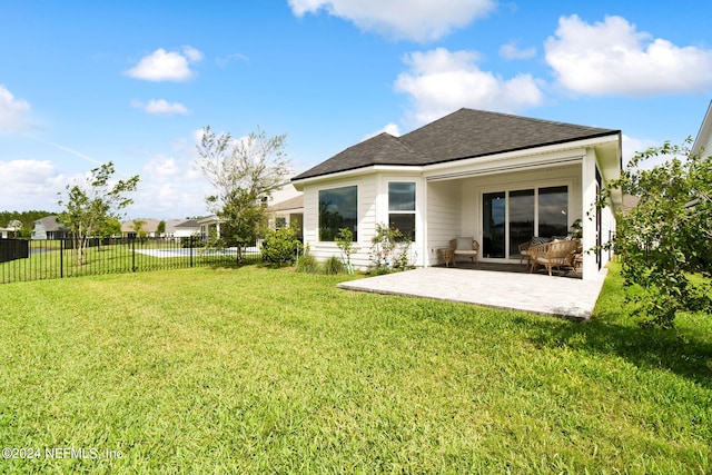 rear view of house featuring a shingled roof, a patio, a lawn, and fence