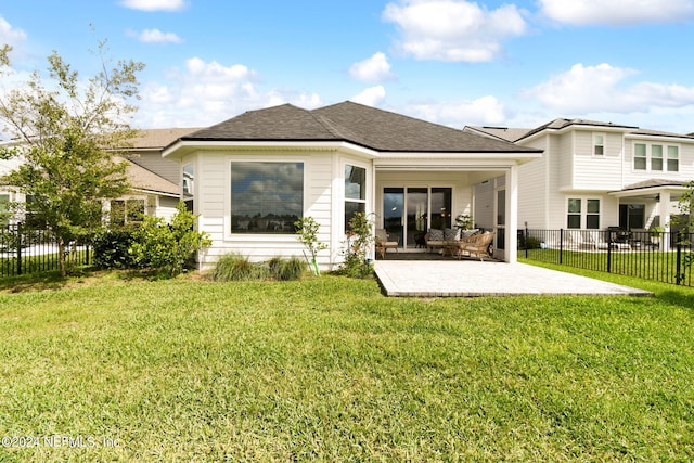 rear view of house with roof with shingles, fence, a lawn, and a patio