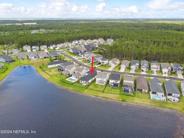 drone / aerial view featuring a water view, a wooded view, and a residential view