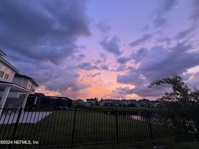 yard at dusk with a residential view and fence