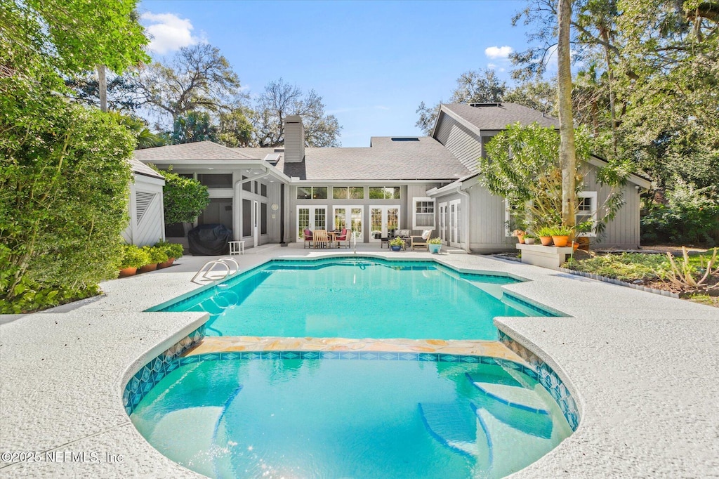 view of pool with french doors, a sunroom, and a patio area