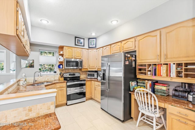 kitchen featuring appliances with stainless steel finishes, built in desk, sink, kitchen peninsula, and light brown cabinets