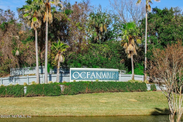 community sign featuring a lawn and a water view