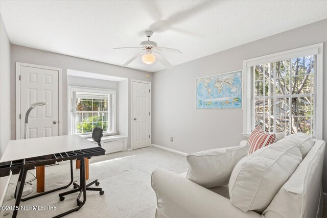 home office featuring ceiling fan, light colored carpet, and a textured ceiling