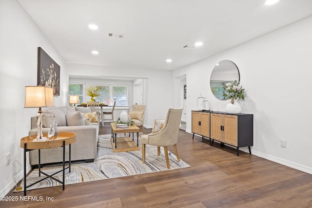 living room with recessed lighting, visible vents, baseboards, and wood finished floors