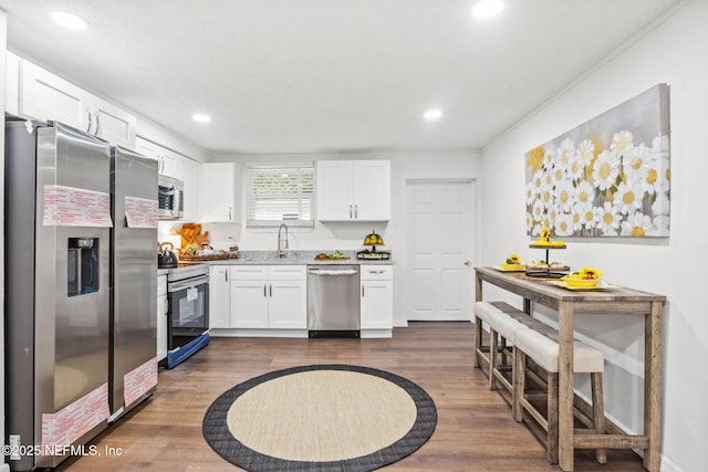 kitchen featuring stainless steel appliances, dark wood-style flooring, white cabinetry, and a sink