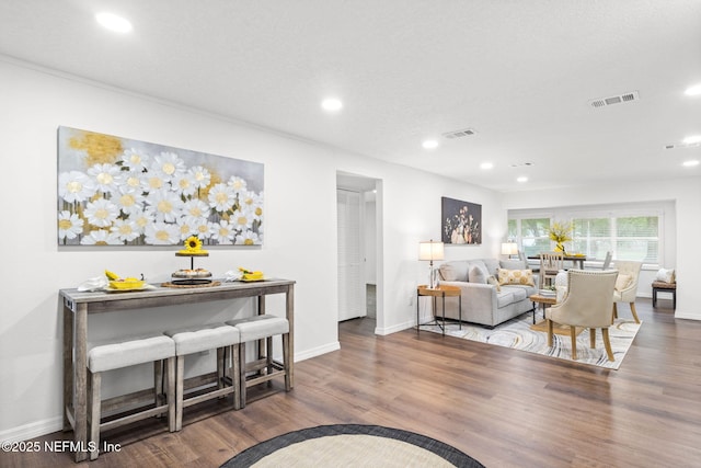 living room featuring baseboards, visible vents, wood finished floors, and recessed lighting