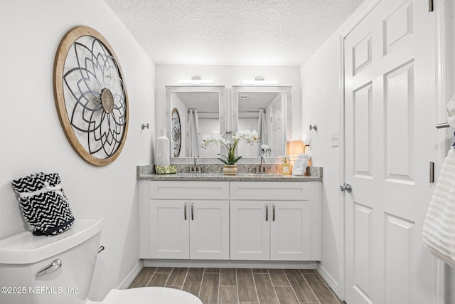 bathroom with toilet, wood tiled floor, baseboards, and a textured ceiling