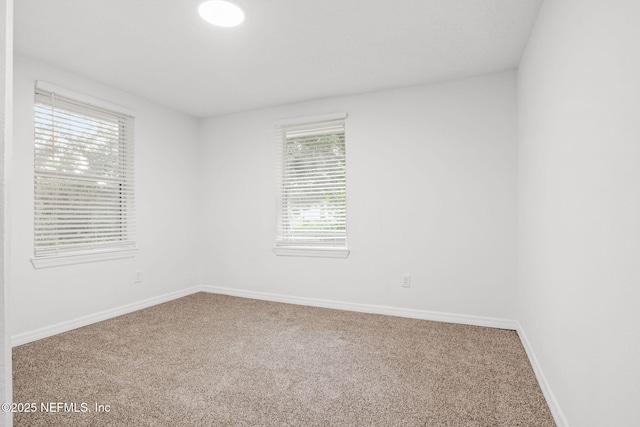 carpeted empty room featuring baseboards