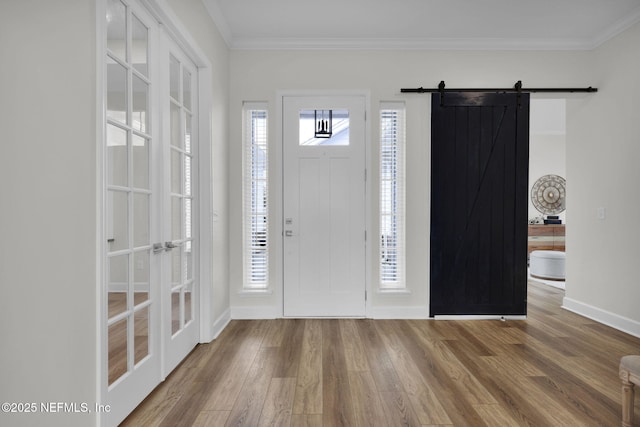 entryway featuring hardwood / wood-style flooring, crown molding, and a barn door