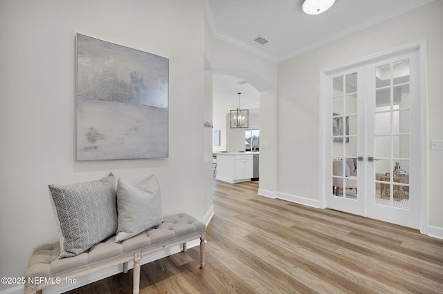 living area with crown molding, light hardwood / wood-style floors, and french doors