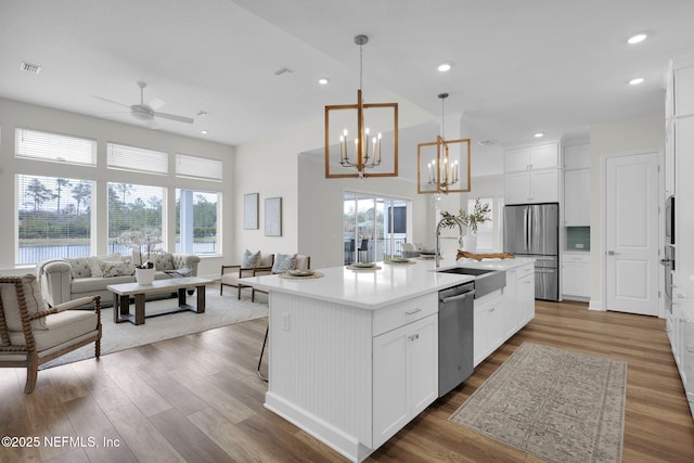 kitchen featuring hanging light fixtures, white cabinets, and a center island with sink