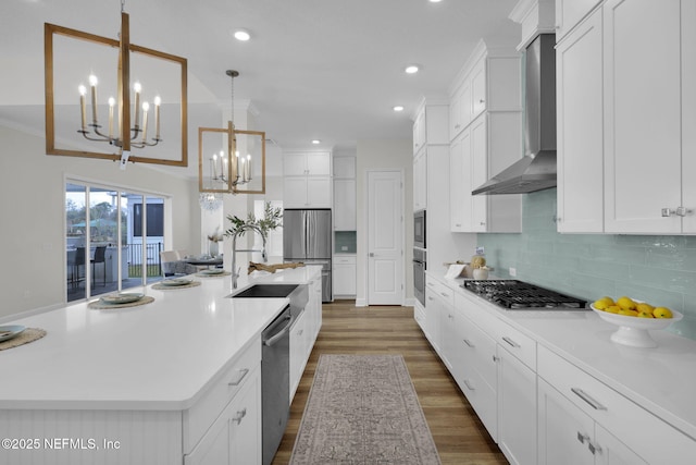 kitchen with pendant lighting, white cabinetry, an island with sink, dark hardwood / wood-style flooring, and wall chimney range hood