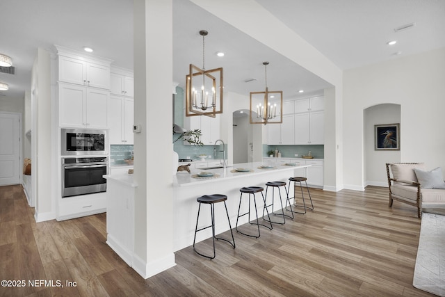 kitchen with pendant lighting, sink, tasteful backsplash, white cabinets, and oven