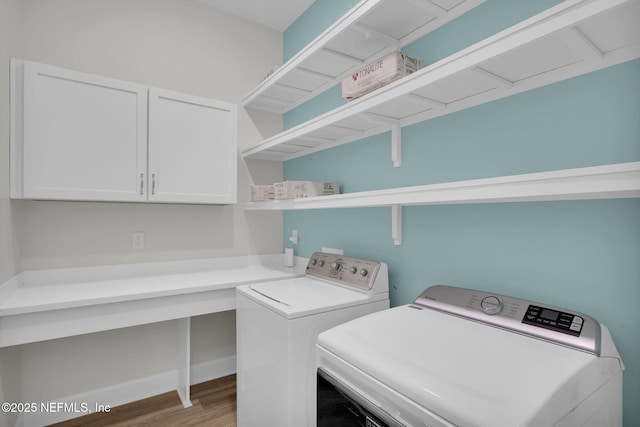 laundry area featuring cabinets, washing machine and clothes dryer, and hardwood / wood-style floors