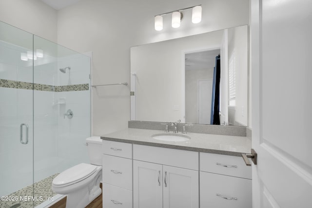 bathroom with a shower with door, vanity, and toilet