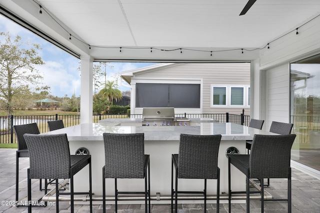 view of patio / terrace featuring a water view, a grill, and a bar