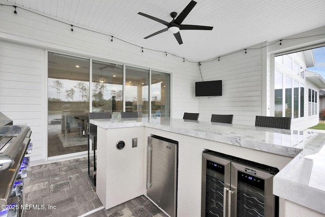 view of patio / terrace with an outdoor kitchen, beverage cooler, ceiling fan, and exterior bar