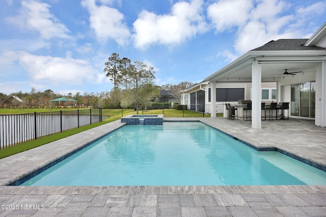 view of swimming pool with a bar, an in ground hot tub, ceiling fan, a water view, and a patio area