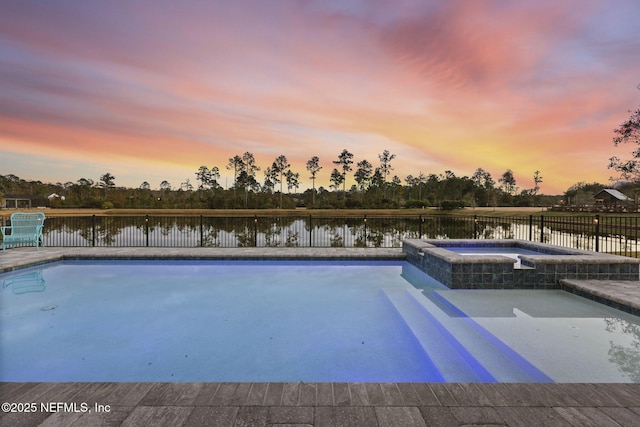 pool at dusk featuring an in ground hot tub, a water view, and a patio