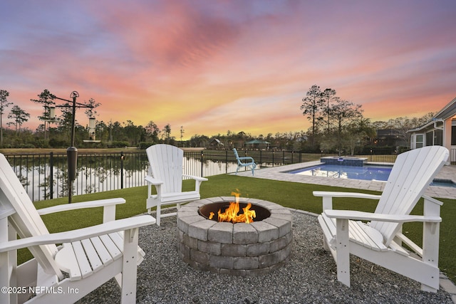 patio terrace at dusk with a fenced in pool, a fire pit, a yard, and a water view