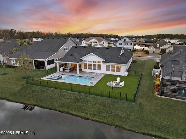 back house at dusk with a patio, a yard, and a sunroom