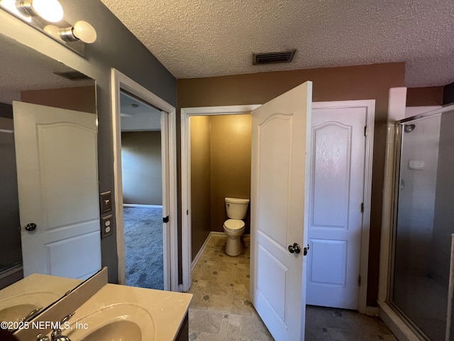 bathroom with an enclosed shower, vanity, toilet, and a textured ceiling