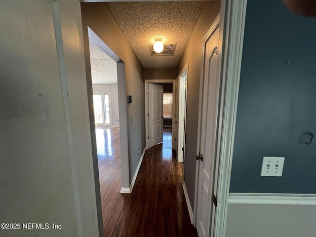 corridor featuring dark wood-type flooring and a textured ceiling