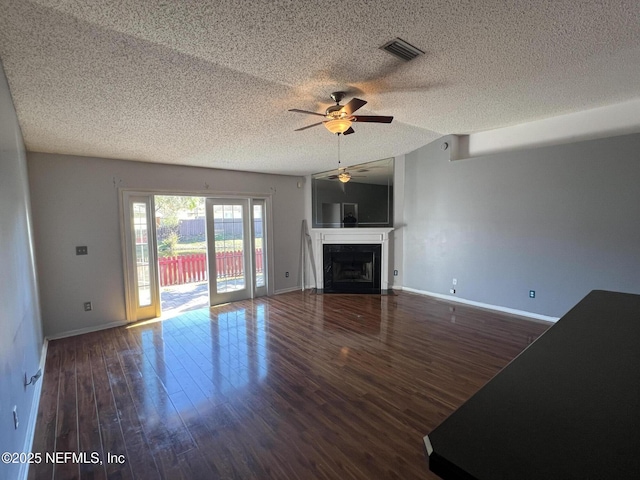 unfurnished living room with dark wood-type flooring, ceiling fan, lofted ceiling, and a textured ceiling