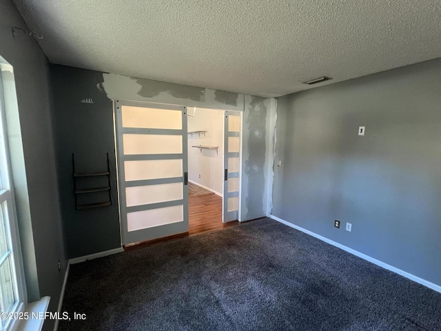 spare room featuring a barn door, carpet floors, and a textured ceiling