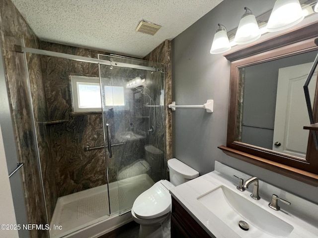 bathroom with vanity, a shower with shower door, toilet, and a textured ceiling