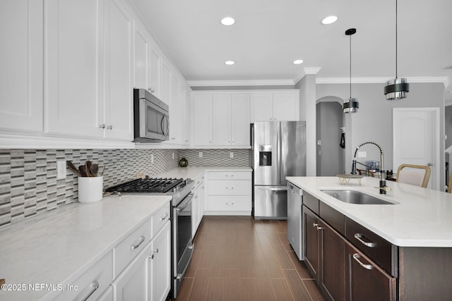 kitchen featuring appliances with stainless steel finishes, white cabinetry, sink, backsplash, and hanging light fixtures