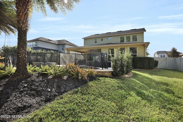 back of house featuring a trampoline and a lawn