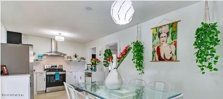 kitchen with electric stove, wall chimney range hood, and white cabinets