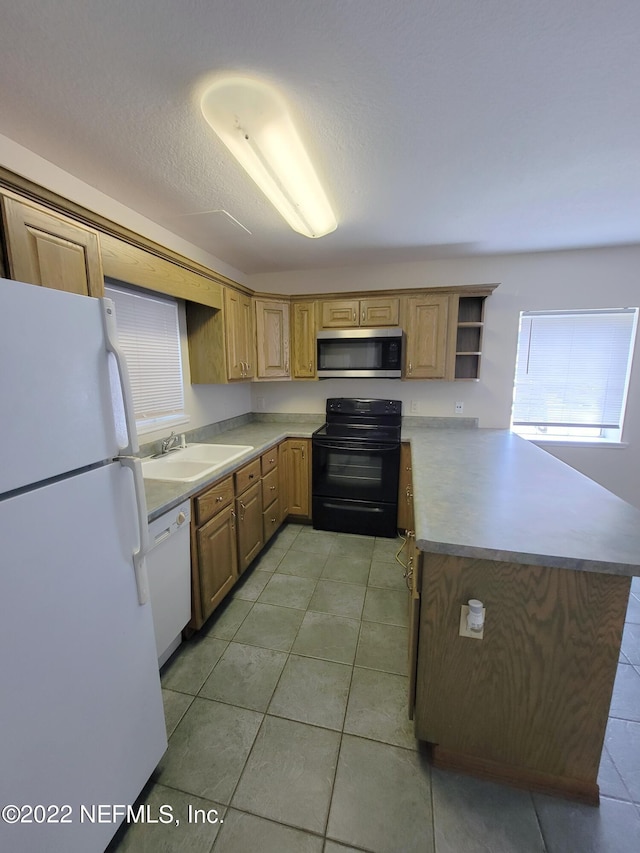 kitchen featuring a healthy amount of sunlight, sink, white appliances, and kitchen peninsula