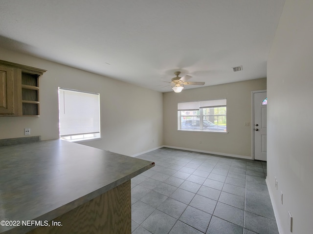 tiled empty room featuring ceiling fan