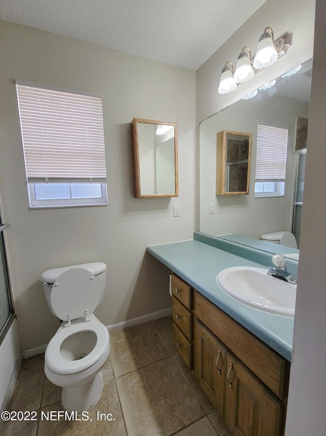 full bathroom with vanity, a textured ceiling, enclosed tub / shower combo, and toilet