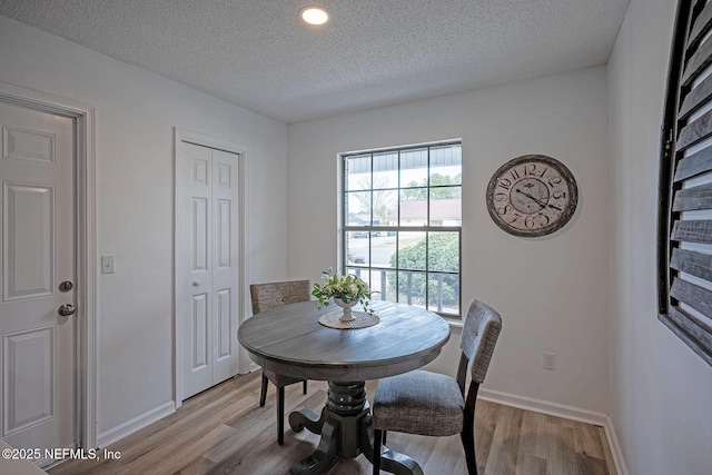 dining space featuring a textured ceiling and light wood-type flooring