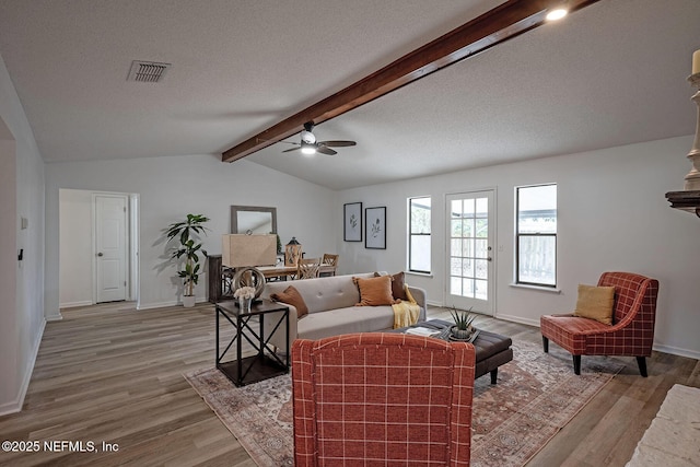 living room with lofted ceiling with beams, ceiling fan, a textured ceiling, and light hardwood / wood-style flooring