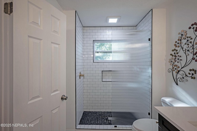 bathroom featuring vanity, tiled shower, a textured ceiling, and toilet