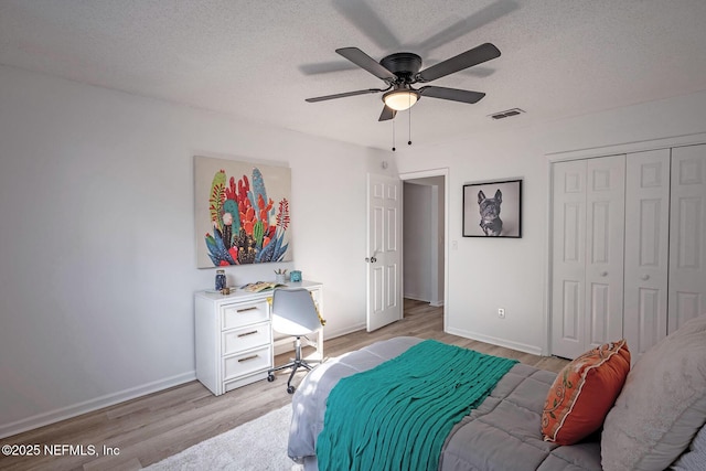 bedroom featuring ceiling fan, a closet, a textured ceiling, and light wood-type flooring