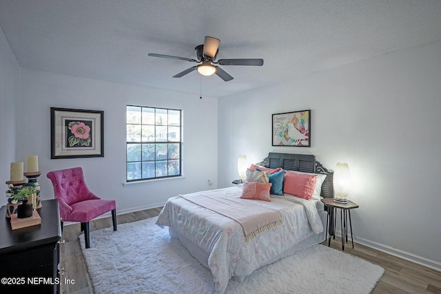 bedroom featuring ceiling fan, hardwood / wood-style floors, and a textured ceiling