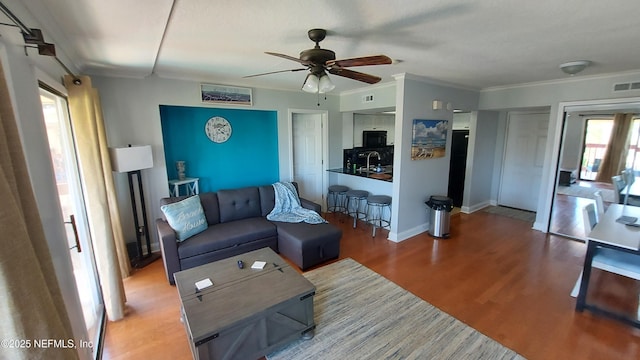 living room featuring crown molding, sink, hardwood / wood-style flooring, and ceiling fan