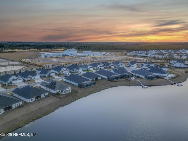 aerial view at dusk with a water view and a beach view