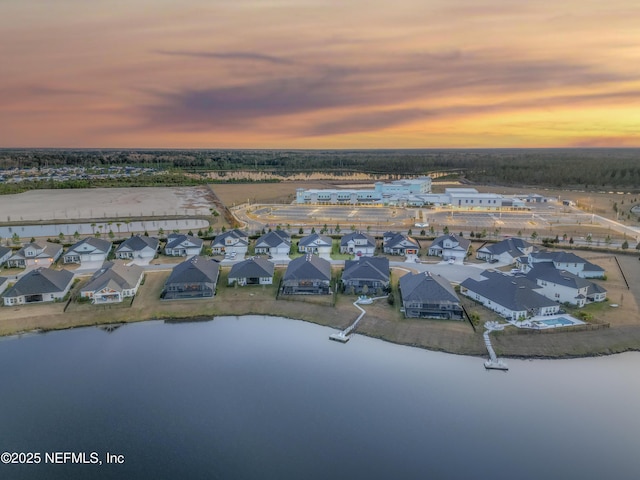 aerial view at dusk featuring a water view